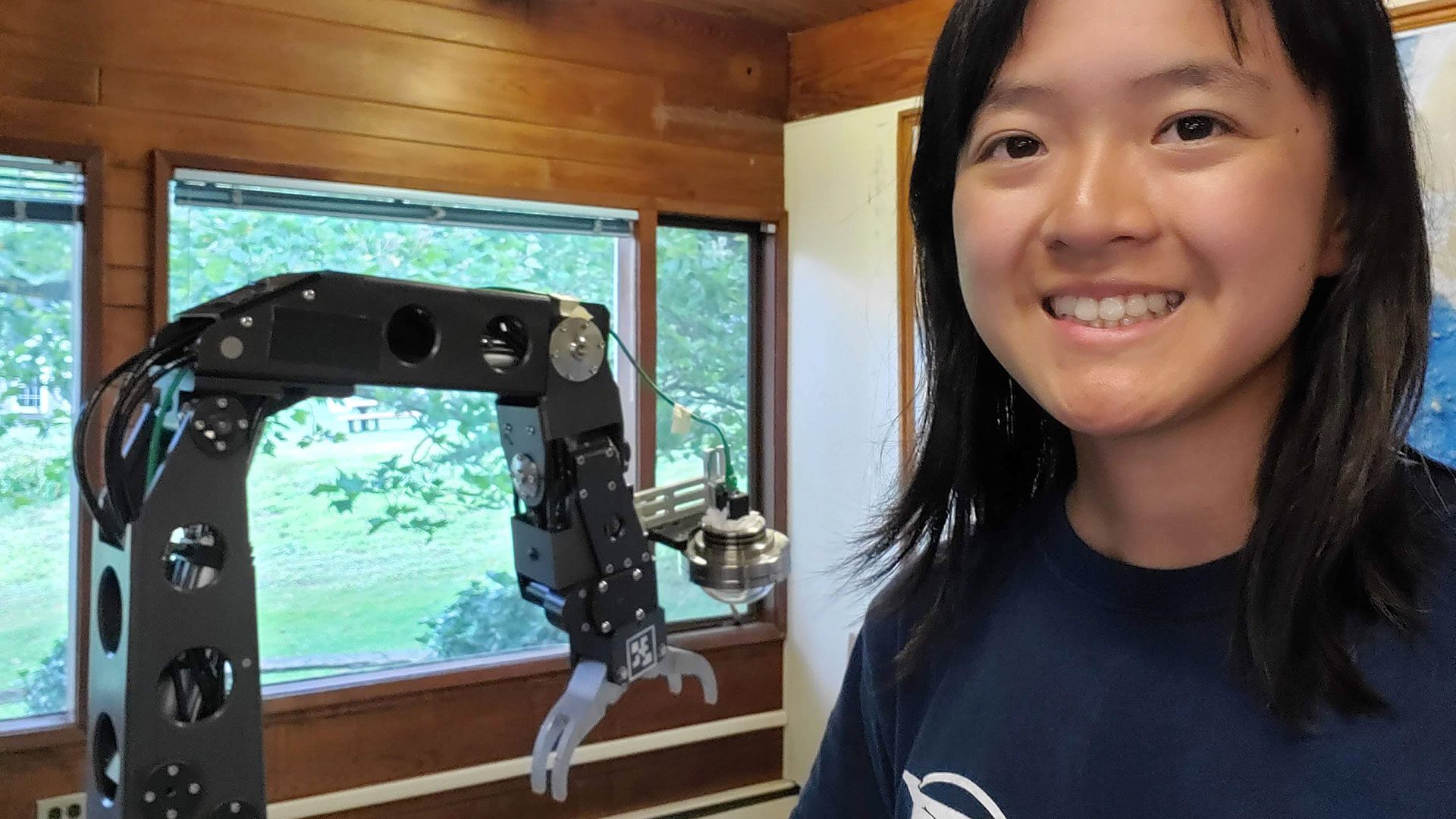 Phung poses with a hydraulic manipulator arm she was developing with the remote interface in the summer of 2021. (Photo courtesy of Amy Phung, © Woods Hole Oceanographic Institution)