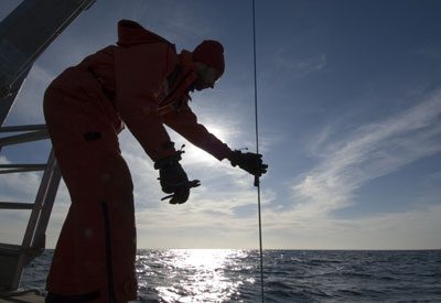 Andrey unclips the temperature loggers from the mooring lines while Ian pulls them up with the winch