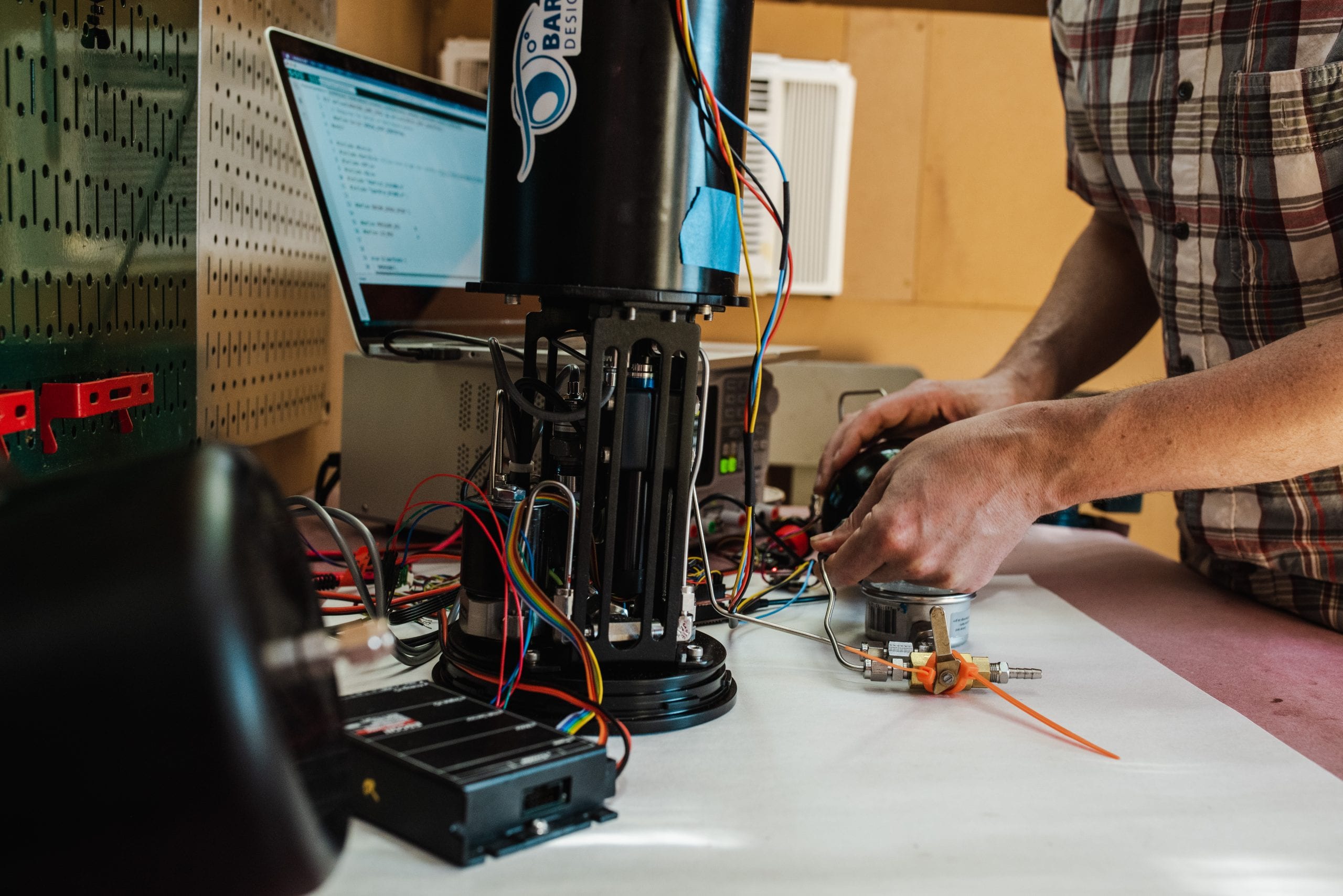 John Reine tests the responsiveness of an open-source buoyancy engine, designed by a former WHOI-engineer Jeremy Paulus, in his shed. (Daniel Hentz, © Woods Hole Oceanographic Institution)