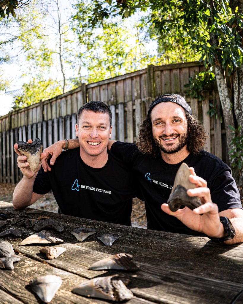 Fossil Exchange owners Brett Garner and Chris Slog hold up megalodon teeth