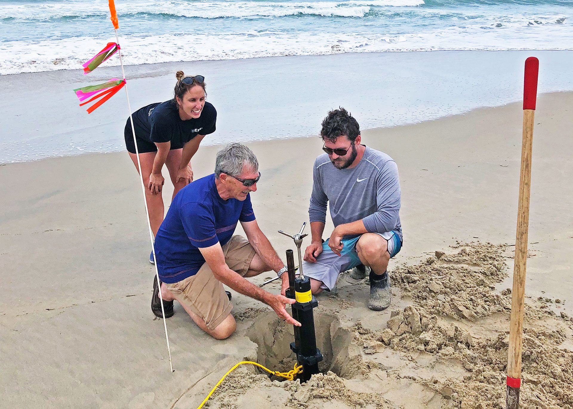 WHOI senior scientist Steve Elgar (middle), research associate Levi Gorrell (right), and U.S. Army oceanographer Kate Brodie (left), deploy a current meter to measure seawater flowing along and across the beach as Hurricane Dorian inundates the North Carolina coast.