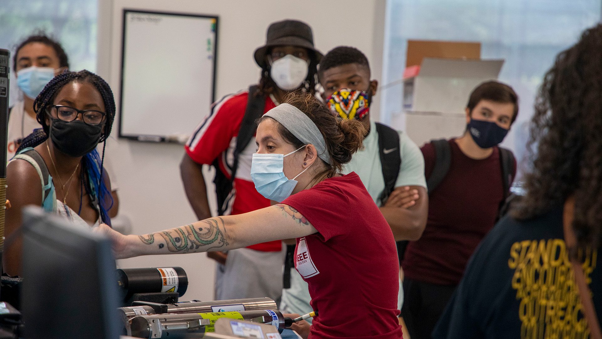 Duran (red shirt) shows high school students some OOI electronics equipment in WHOI's LOSOS Building. (Photo by Jayne Doucette, © Woods Hole Oceanographic Institution)