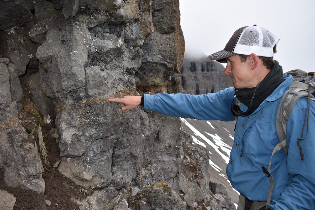 Horton points out a contact between lava flows on Baffin Island, Arctic Canada, that are precursors to the eruptions on Iceland today. (Photo by Paul Asimow, © Woods Hole Oceanographic Institution)