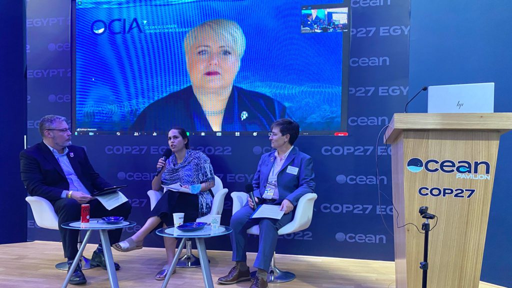 At the COP27 Ocean Pavilion, panelists (left to right) Sam Harp (WHOI), Whitney Johnston (Salesforce, with microphone), Kathryn Hautanen (ADI, on screen), and moderator Véronique LaCapra (WHOI) discuss the potential of science-industry collaboration to combat climate change. (Photo by Ken Kostel, WHOI)