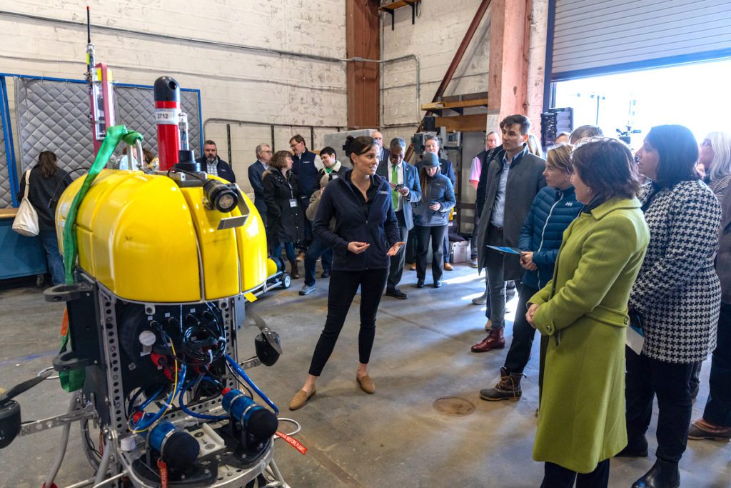 WHOI engineer Molly Curran tells the governor and her team about Mesobot, a hybrid autonomous underwater vehicle she helped develop to study animals in the ocean twilight zone. (Photo by Joshua Qualls, Governor's Press Office)