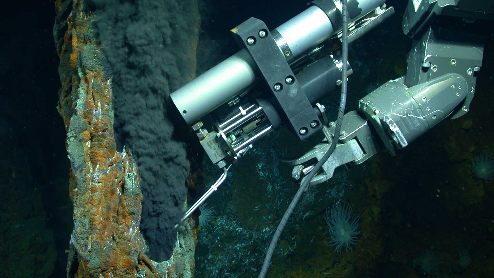The slender snorkel of an Isobaric Gas-Tight sampler (IGT) draws a sample of hydrothermal fluids spewing out of a hydrothermal vent