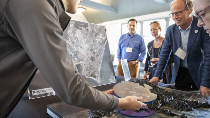People look at a 3D topographical model of Woods Hole flood risks