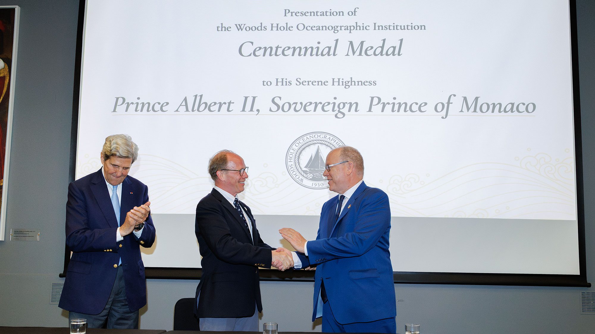 WHOI President &amp; Director Peter de Menocal (center) awards the Institution's new Centennial Medal to His Serene Highness, Prince Albert II of Monaco with Secretary John Kerry on stage. (Photo by Michael Alesi / Palais princier)