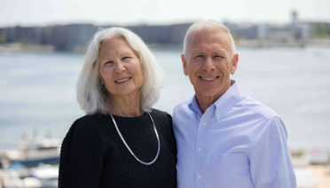 Kim Gassett-Schiller and Phil Schiller standing in front of Boston Harbor