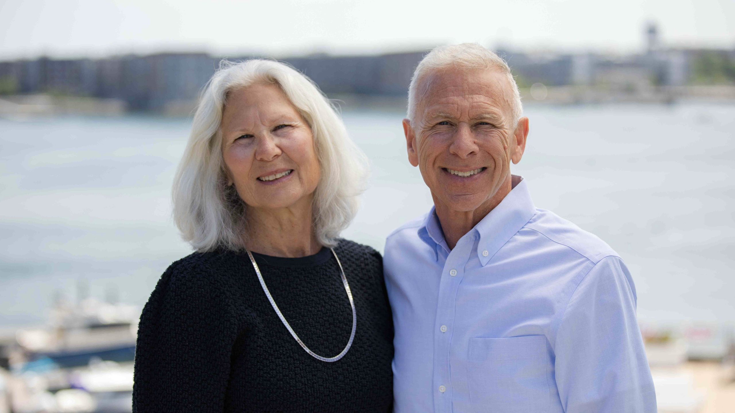 Kim Gassett-Schiller and Phil Schiller standing in front of Boston Harbor