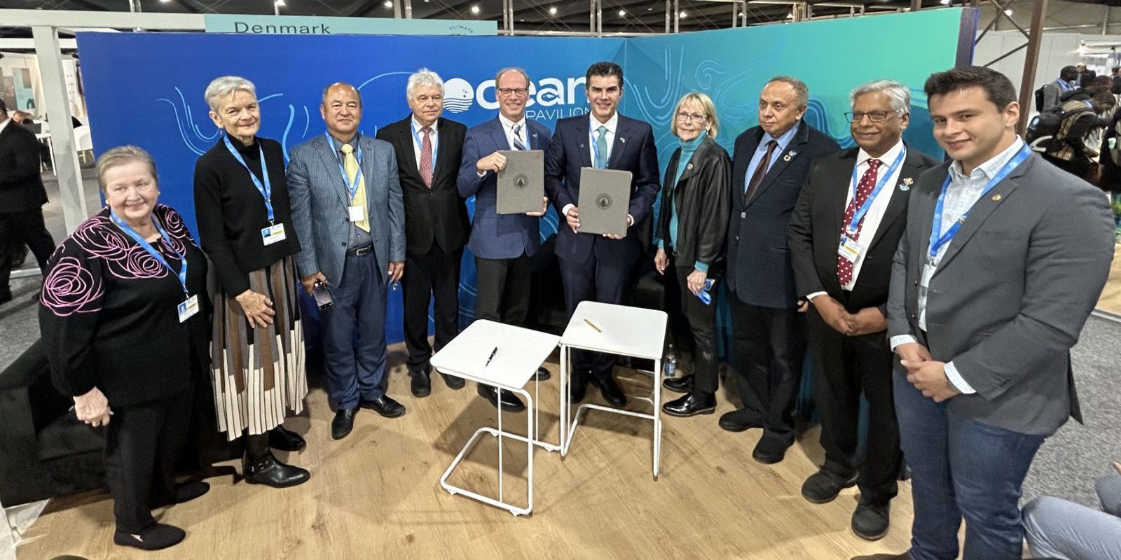 WHOI’s Peter de Menocal (center, left) with the Governor of Para Helder Barbalho (center, right) signed an MOU outlining mutual goals in advance of COP30.  They are joined by partners of the Ocean Pavilion. (Photo by: Kalina Grabb, ©Woods Hole Oceanographic Institution)